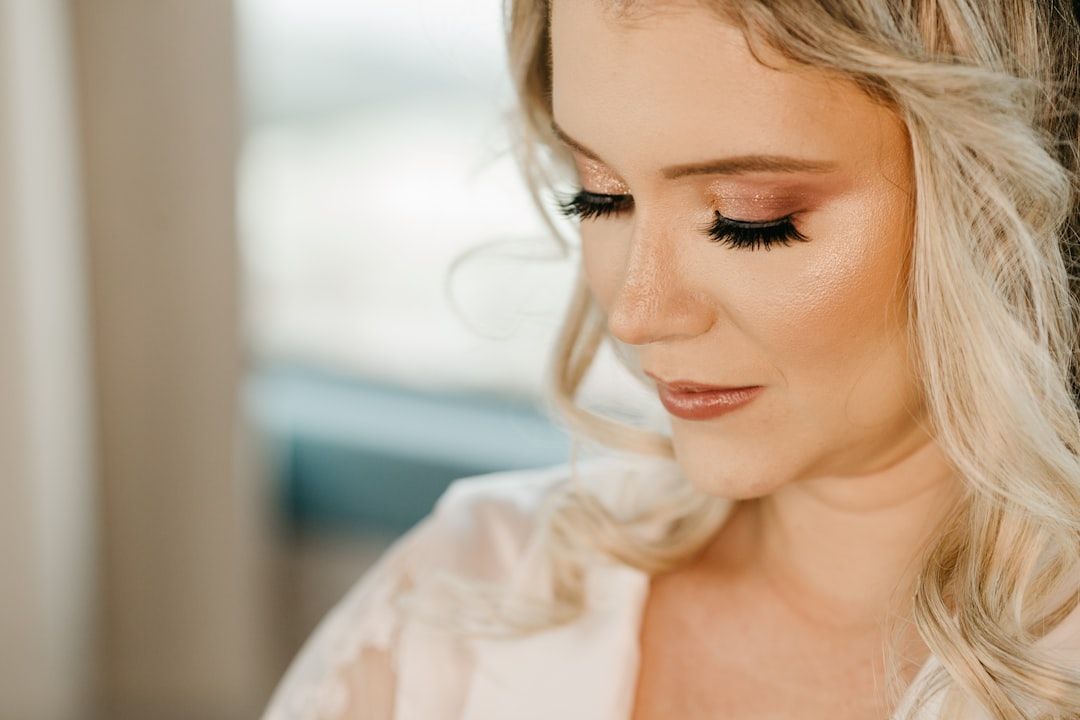 Närbild på en kvinna med elegant festmakeup och lockat blont hår inför ett event.